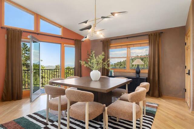 The dining table set for eight beside the view windows, deck door open