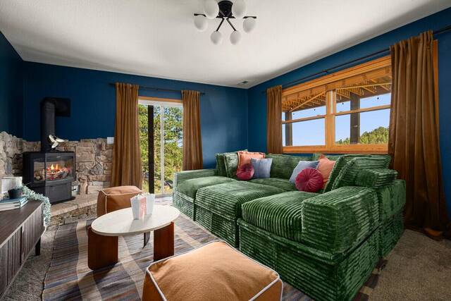 The living room, with a green sectional, lit wood stove and stone hearth