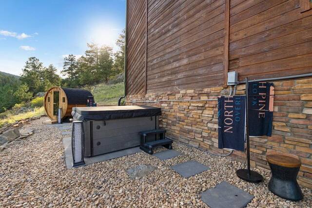 The hot tub and barrel sauna against the stone and timber wall