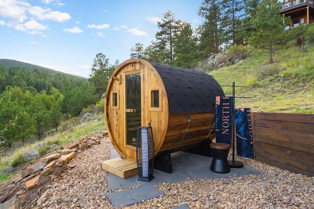 The barrel sauna outside, with the hillside behind it
