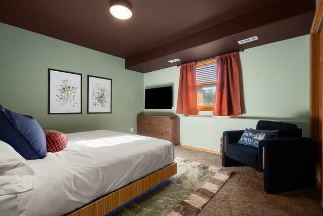 A bedroom with green walls, a bed and a reading chair