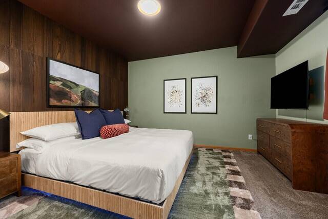 A bedroom with wood panelling and a wall-mounted television